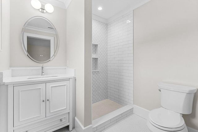 bathroom featuring toilet, vanity, baseboards, tiled shower, and tile patterned floors