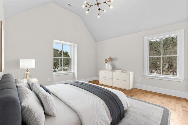 bedroom featuring baseboards, visible vents, wood finished floors, an inviting chandelier, and vaulted ceiling