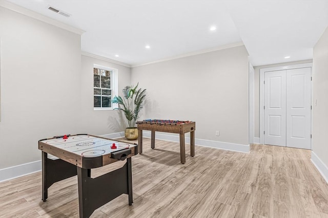 rec room featuring crown molding, light wood-style floors, visible vents, and baseboards