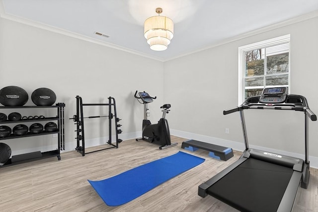 exercise area featuring ornamental molding, visible vents, baseboards, and wood finished floors