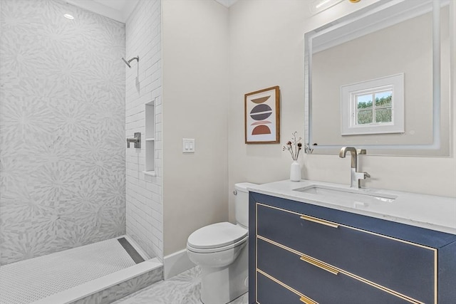 bathroom with marble finish floor, tiled shower, vanity, and toilet