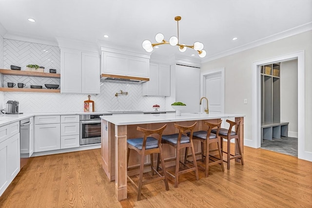 kitchen featuring open shelves, light countertops, stainless steel oven, a sink, and light wood-type flooring