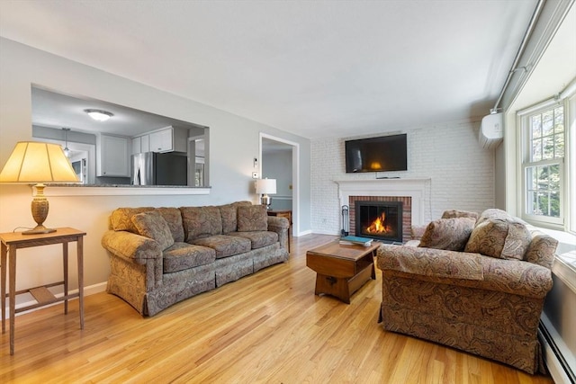 living room with light wood-style floors, baseboards, a baseboard heating unit, and a fireplace