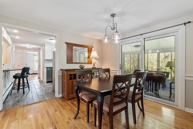 dining space featuring a baseboard heating unit and light wood-style floors