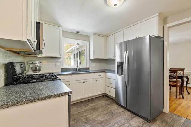kitchen with stainless steel appliances, dark countertops, a sink, and tasteful backsplash