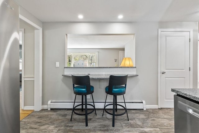 kitchen with stainless steel dishwasher, wood finished floors, a baseboard radiator, a breakfast bar, and recessed lighting