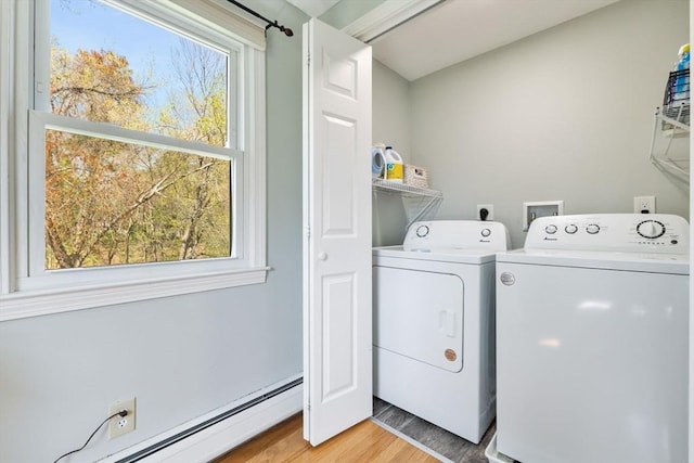 clothes washing area featuring a baseboard radiator, laundry area, light wood-style flooring, and washer and dryer
