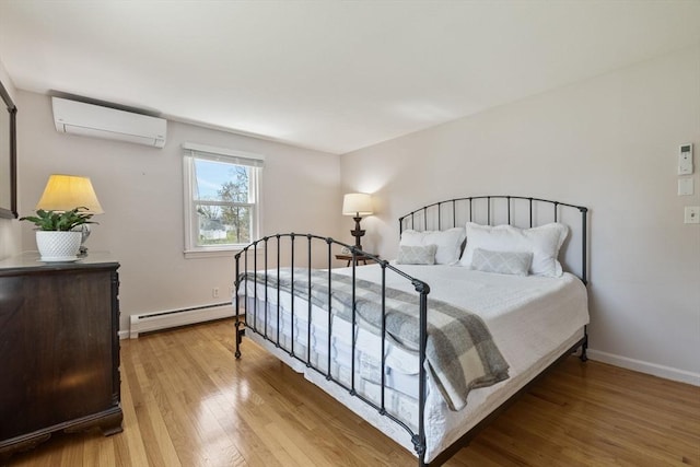 bedroom with light wood-type flooring, baseboards, a wall unit AC, and a baseboard heating unit