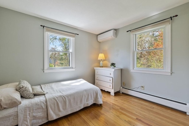 bedroom featuring an AC wall unit, a baseboard radiator, and light wood finished floors