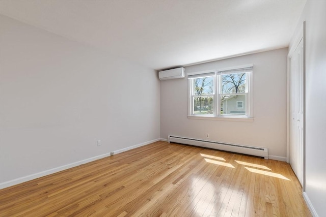 spare room featuring light wood-style floors, a wall mounted AC, baseboards, and a baseboard radiator