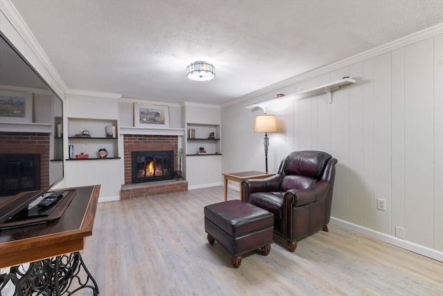 living area with a textured ceiling, ornamental molding, wood finished floors, and a fireplace
