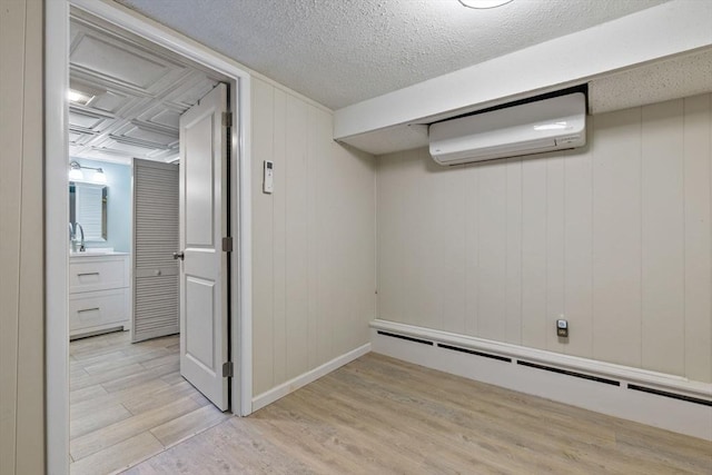 interior space featuring a baseboard radiator, light wood-type flooring, and a wall mounted air conditioner
