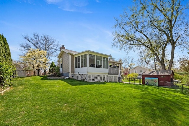rear view of property featuring a yard, a chimney, a fenced backyard, and a sunroom