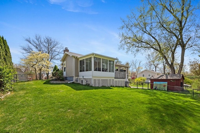 back of property featuring a fenced backyard, a yard, a chimney, and a sunroom