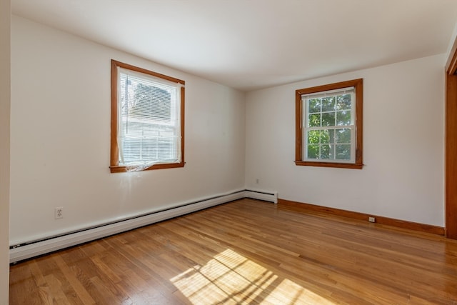 unfurnished room with a baseboard heating unit and light wood-type flooring