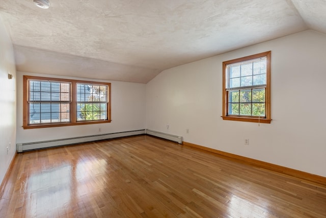 additional living space with hardwood / wood-style floors, a wealth of natural light, vaulted ceiling, and a textured ceiling