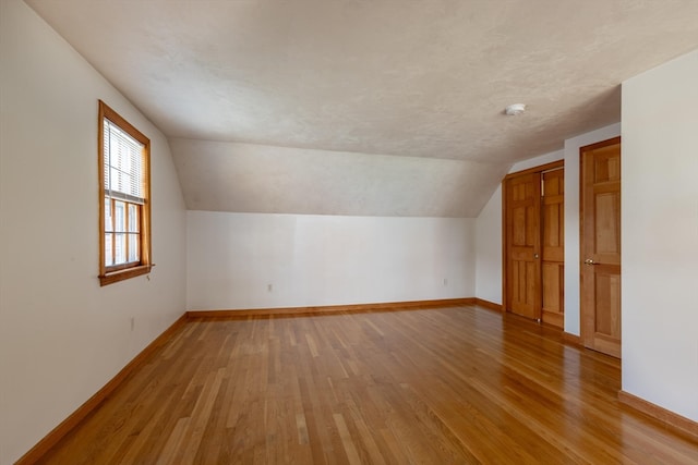 additional living space with vaulted ceiling and light wood-type flooring