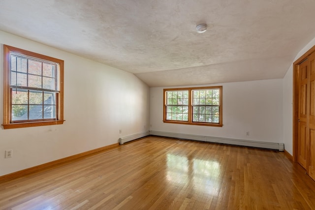 interior space with vaulted ceiling, light hardwood / wood-style flooring, a textured ceiling, and a baseboard radiator