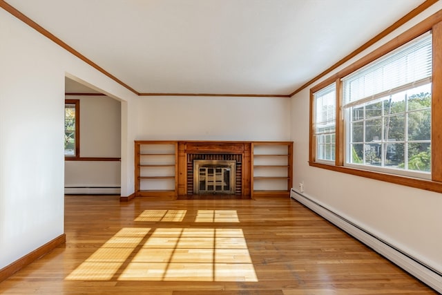 unfurnished living room with baseboard heating, hardwood / wood-style flooring, and a wealth of natural light