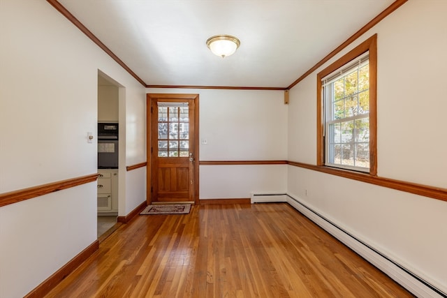 interior space featuring ornamental molding, light hardwood / wood-style floors, and a baseboard heating unit