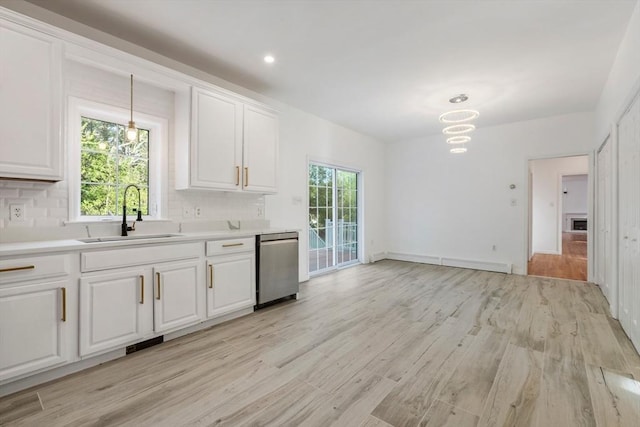 kitchen with dishwasher, a sink, decorative backsplash, light countertops, and white cabinets