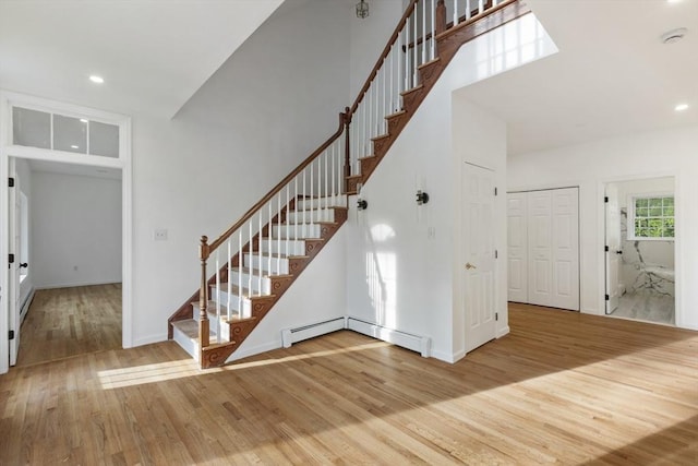 staircase with recessed lighting, a towering ceiling, and wood finished floors