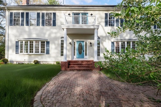 colonial home with a balcony and a chimney