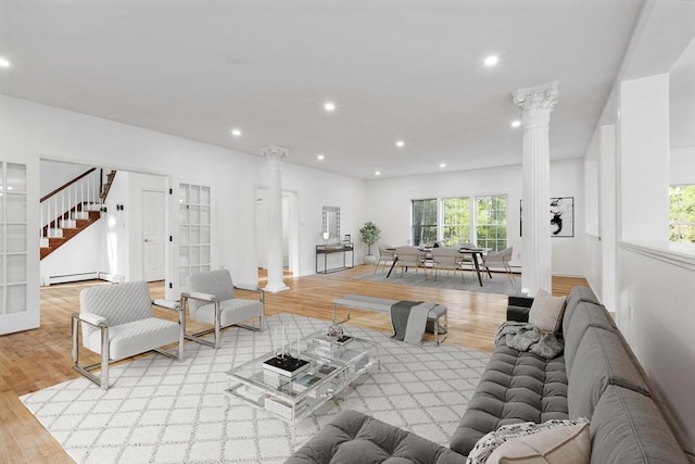 living area with stairs, ornate columns, light wood-type flooring, recessed lighting, and a baseboard radiator