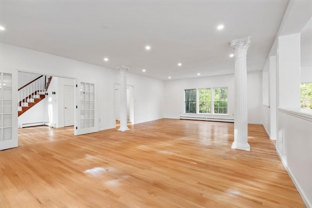 unfurnished living room featuring light wood finished floors, baseboard heating, and ornate columns