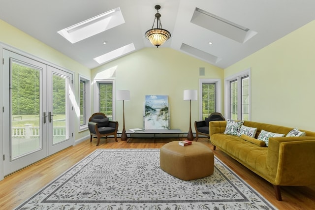 living room with light hardwood / wood-style flooring, vaulted ceiling with skylight, a baseboard radiator, and french doors