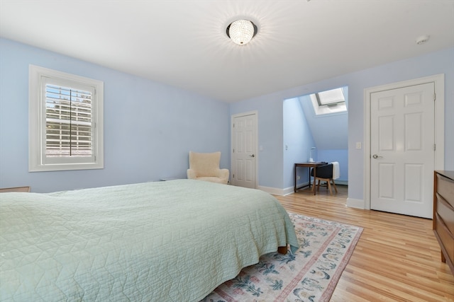 bedroom featuring a skylight and light hardwood / wood-style floors