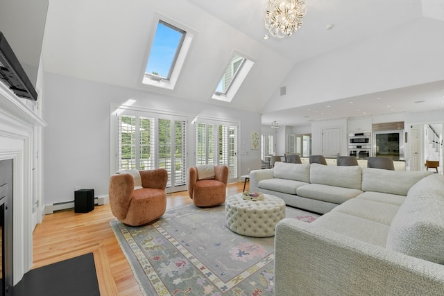 living room with an inviting chandelier, light hardwood / wood-style floors, high vaulted ceiling, a skylight, and a baseboard heating unit