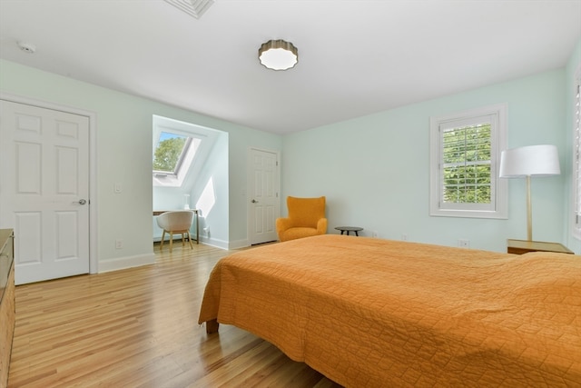 bedroom with light hardwood / wood-style floors, multiple windows, and a skylight