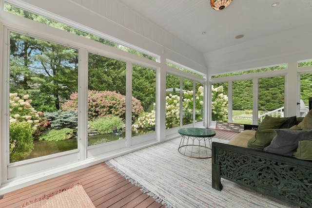 sunroom featuring vaulted ceiling and a water view