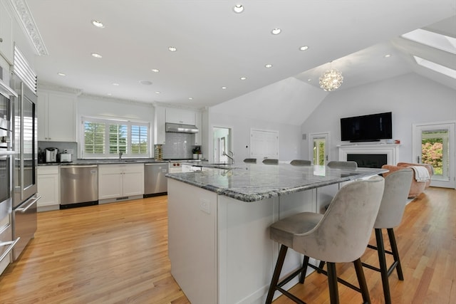 kitchen featuring dishwasher, light wood-type flooring, lofted ceiling, and white cabinetry