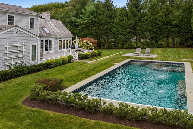 view of pool featuring pool water feature, a deck, and a lawn