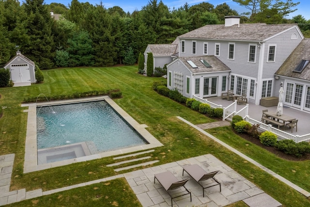 view of pool with a lawn, pool water feature, a patio area, and a storage shed