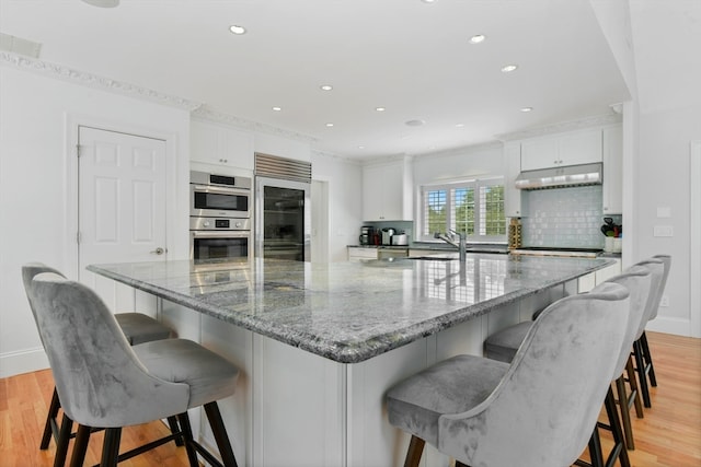 kitchen featuring stainless steel appliances, light wood-type flooring, and white cabinetry