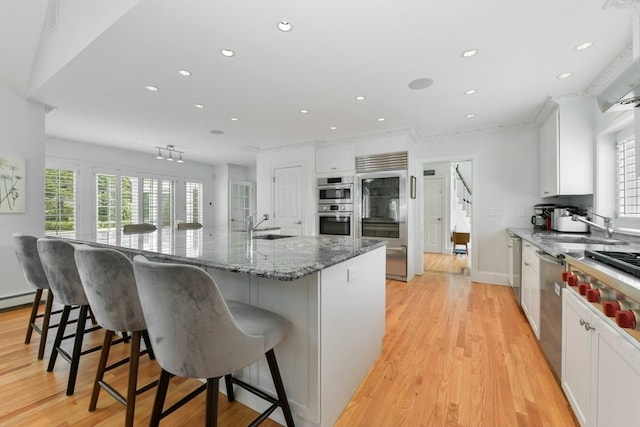 kitchen with a large island, stainless steel appliances, dark stone counters, and light hardwood / wood-style flooring