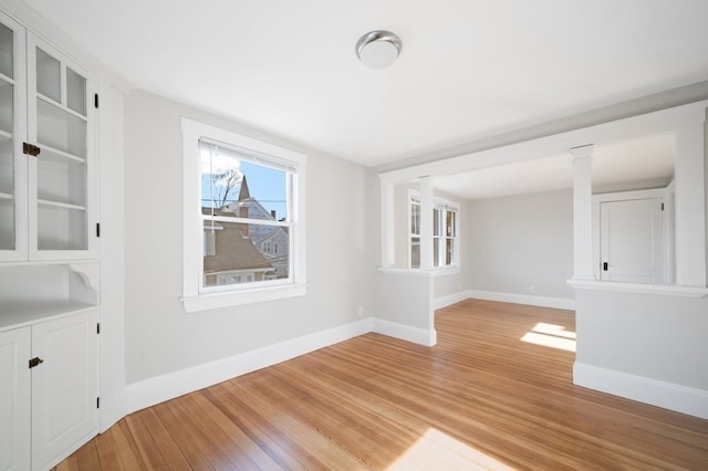 unfurnished dining area featuring light hardwood / wood-style flooring and ornate columns