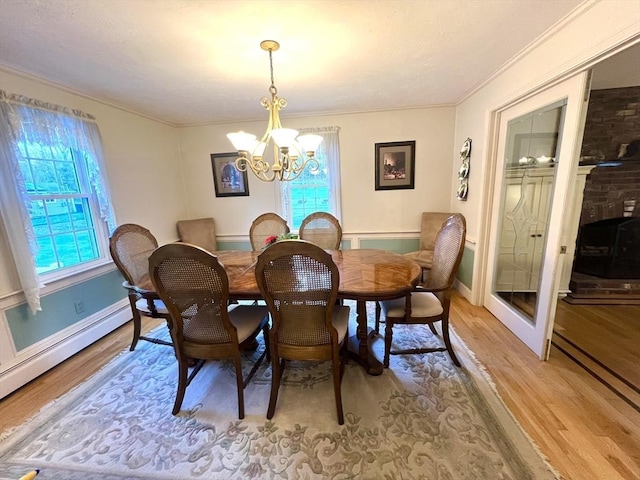 7 Glen Ave, Millbury, MA 01527 - dining space with crown molding, baseboards, a baseboard heating unit, light wood-style flooring, and a notable chandelier