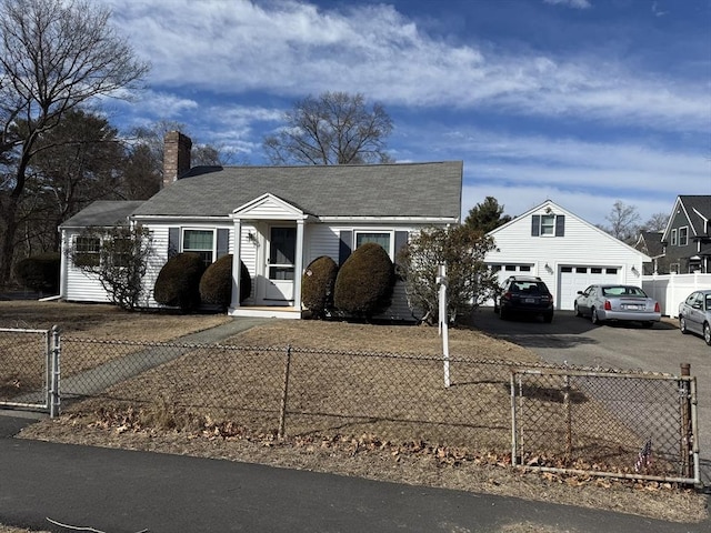 view of front of home with an outbuilding, a gate, a chimney, a fenced front yard, and aphalt driveway