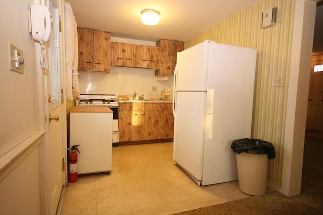 kitchen featuring white appliances, light floors, brown cabinetry, and light countertops