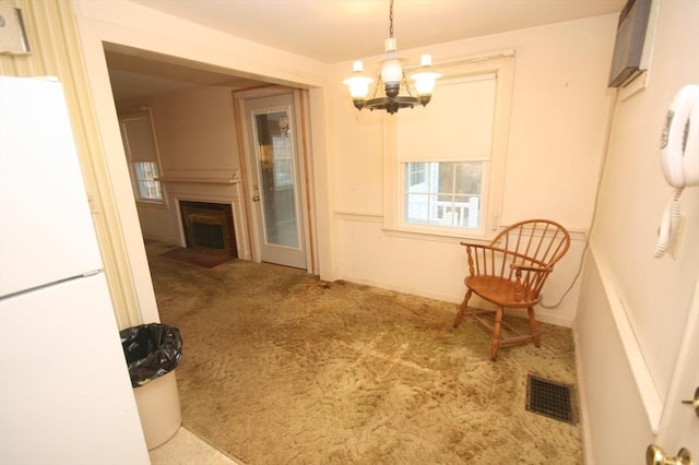 dining room featuring visible vents, a fireplace with flush hearth, a chandelier, and carpet flooring