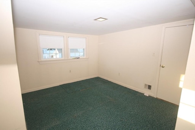 unfurnished room featuring baseboards, visible vents, and dark carpet