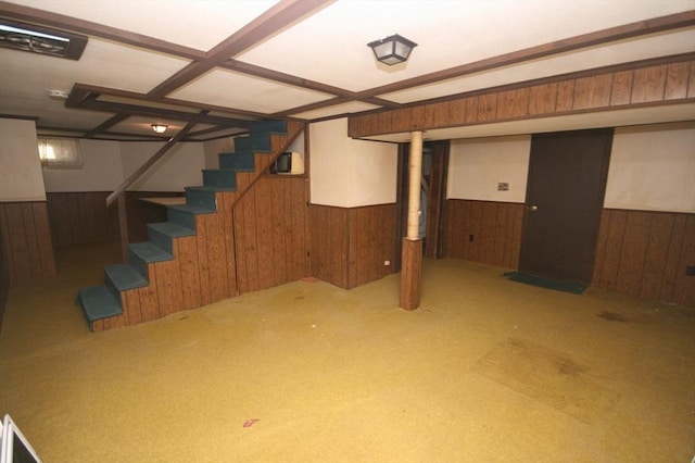 finished basement with stairway, wooden walls, and a wainscoted wall