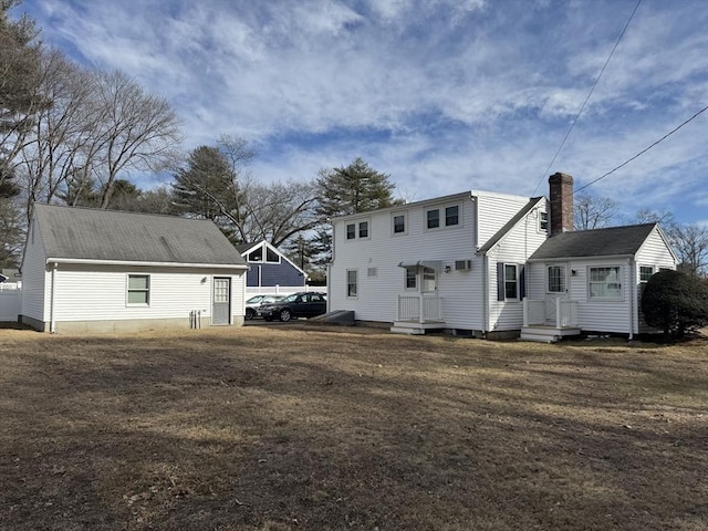 rear view of property featuring a yard and a chimney