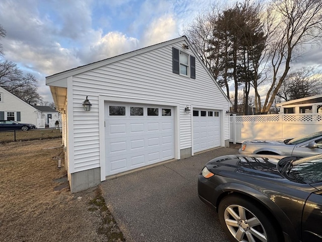 garage featuring driveway and fence