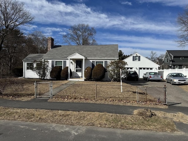 view of front facade featuring aphalt driveway, an outbuilding, a fenced front yard, and a gate