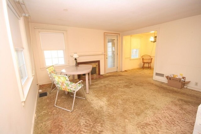 carpeted dining space with a fireplace with flush hearth and visible vents